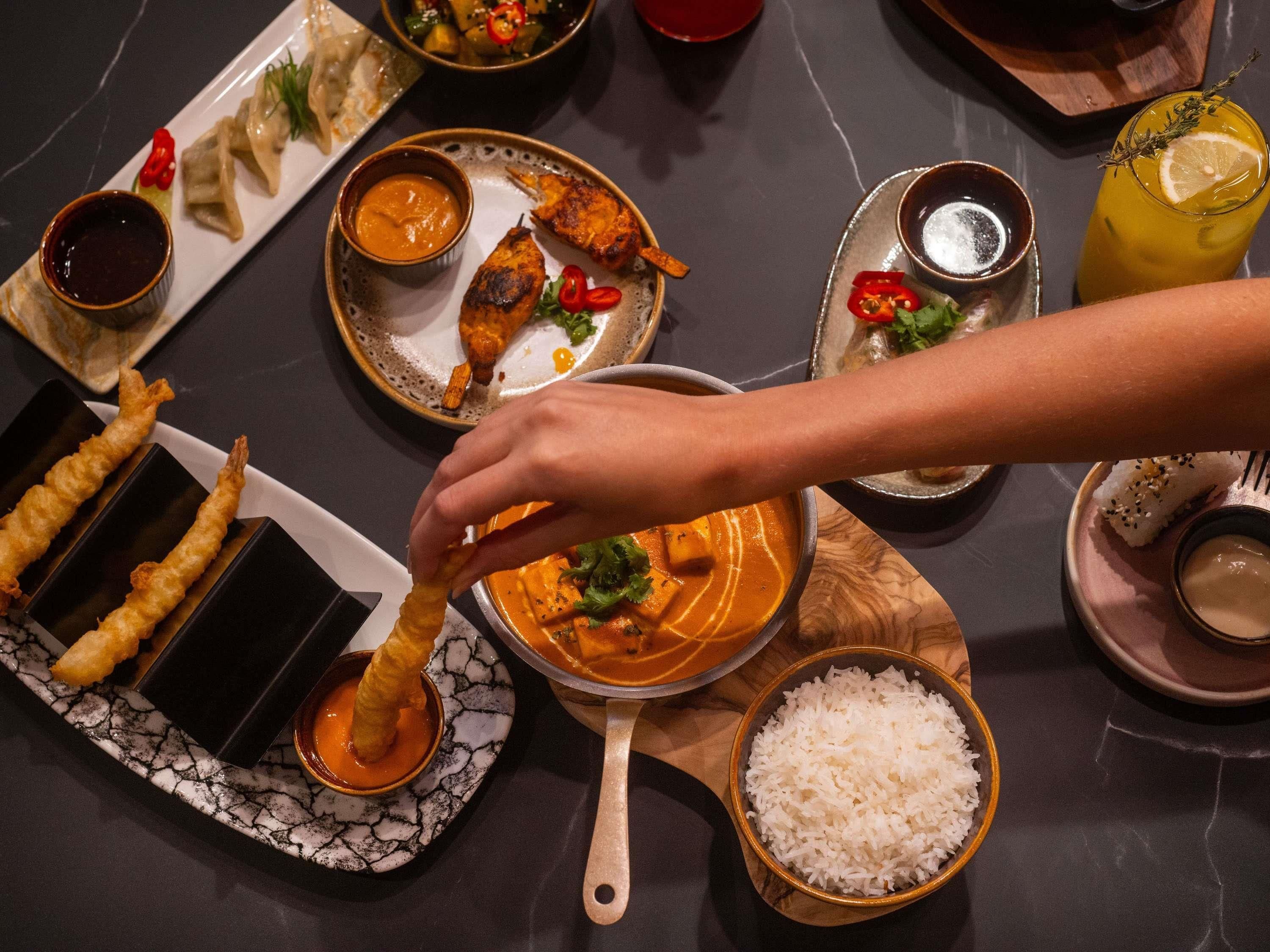 A dining table with various dishes, including a bowl of curry, rice, and fried items.