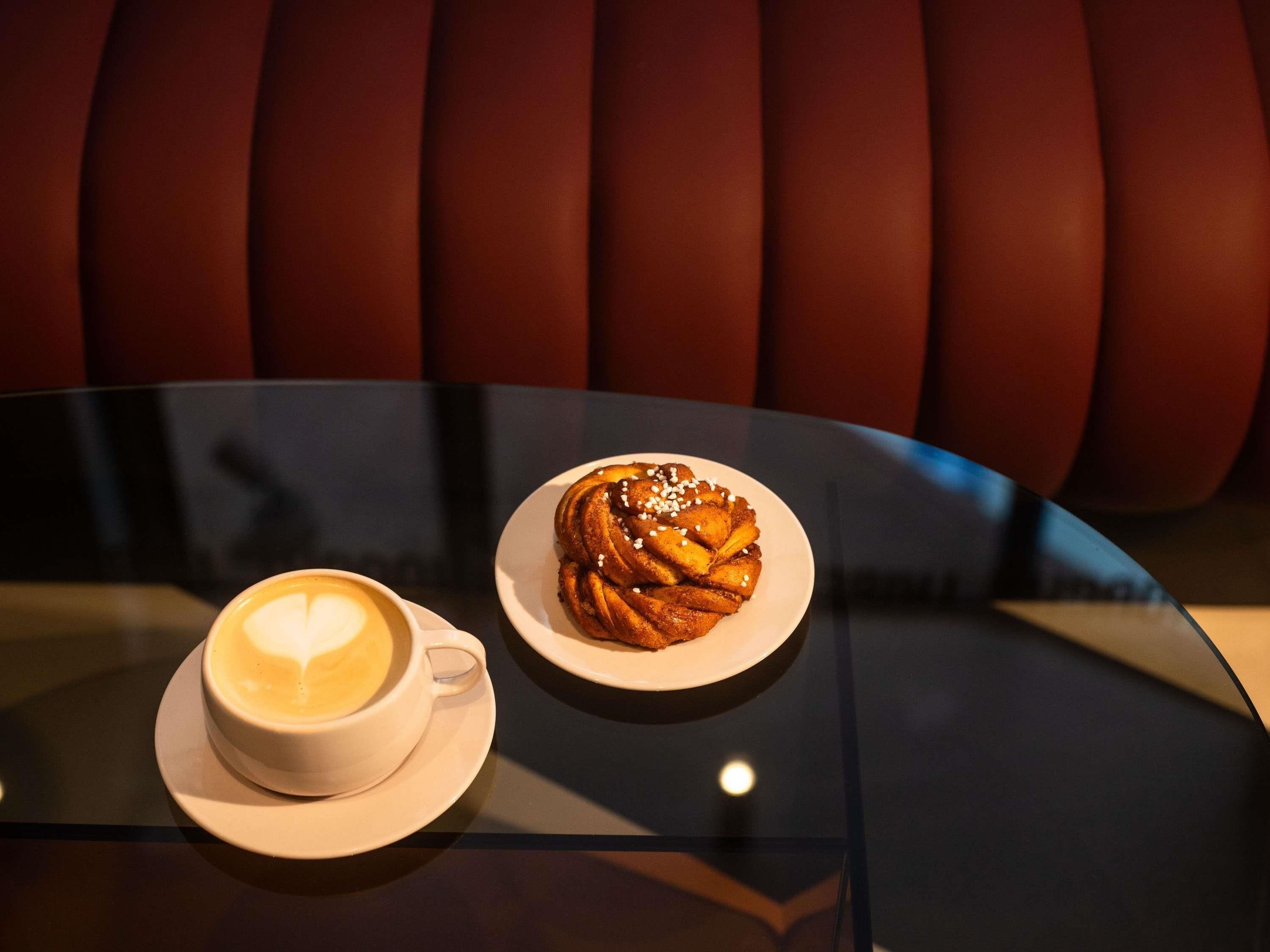 A table with a plate of cinnamon rolls and a cup of coffee.
