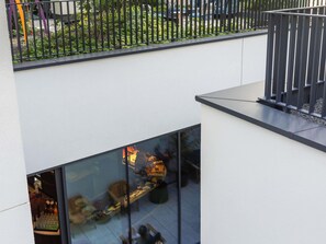A modern building with a glass facade, a balcony with a metal railing, and a garden area visible through the railing. - TRIBE Krakow Old Town (Kraków)