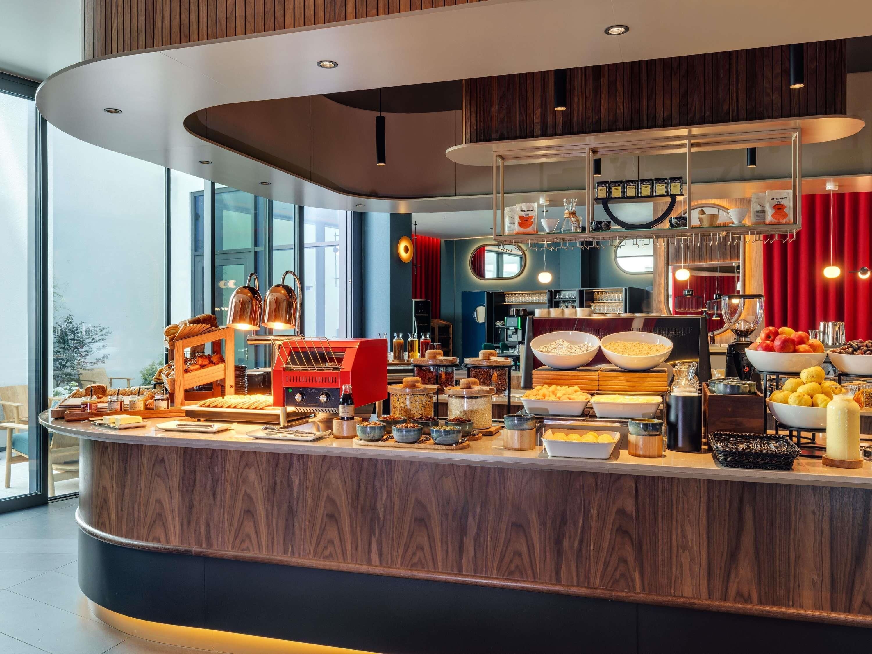 A breakfast buffet with a coffee machine, various food items, and a coffee plant display.