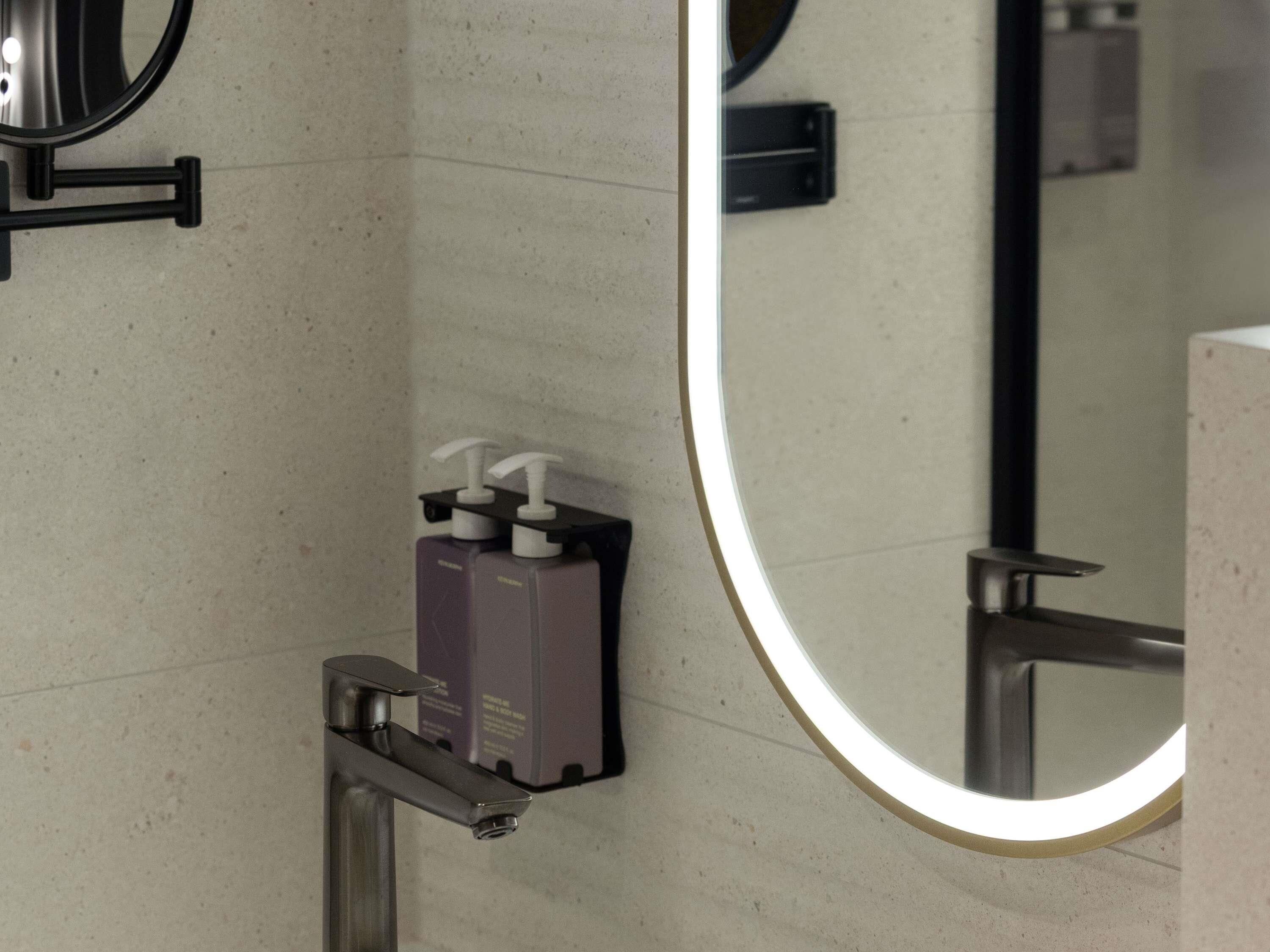 A bathroom with a mirror, a soap dispenser, and a hand dryer.