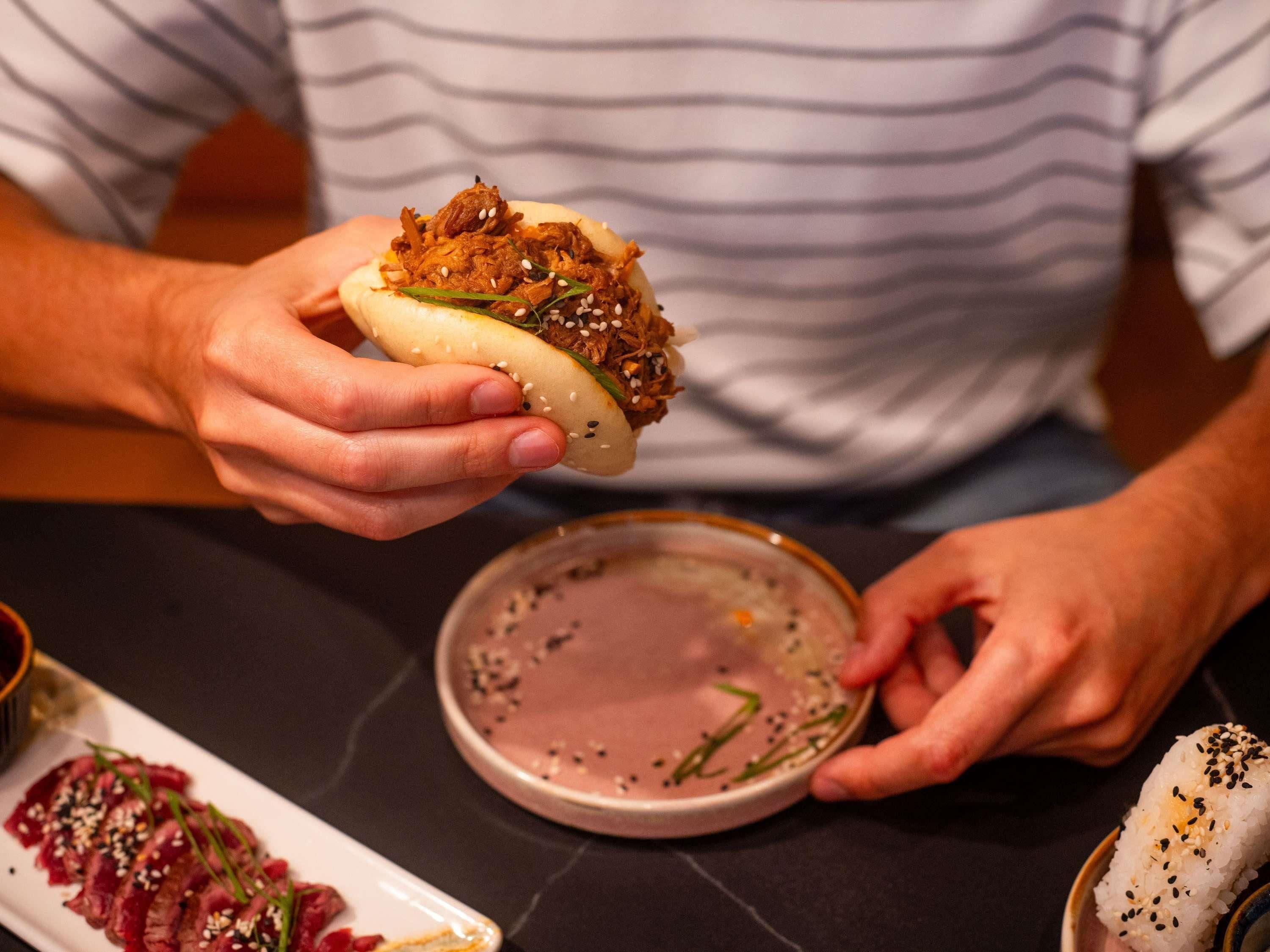 Una persona sosteniendo un sándwich con semillas de sésamo.