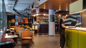 Un interior moderno con una zona de bar, asientos y una persona trabajando en un mostrador.