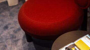 A red chair with a cushion, a small table, and a magazine on the table.