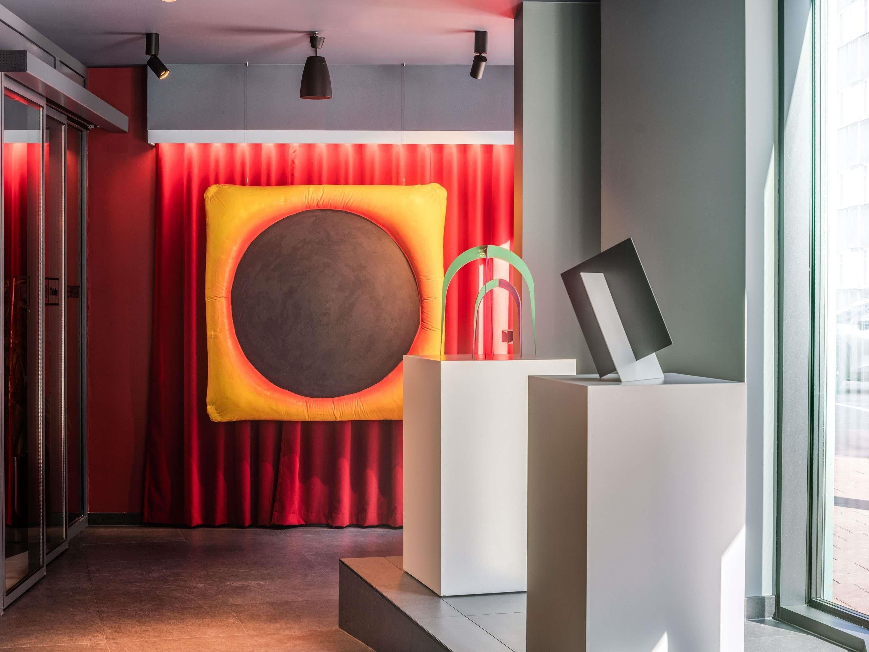 A modern reception area with a large circular wall decoration, a reception desk, and a glass door entrance.