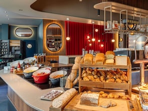 A buffet area with various food items, a coffee machine, and a bar area with glasses and bottles. - TRIBE Krakow Old Town (Kraków)