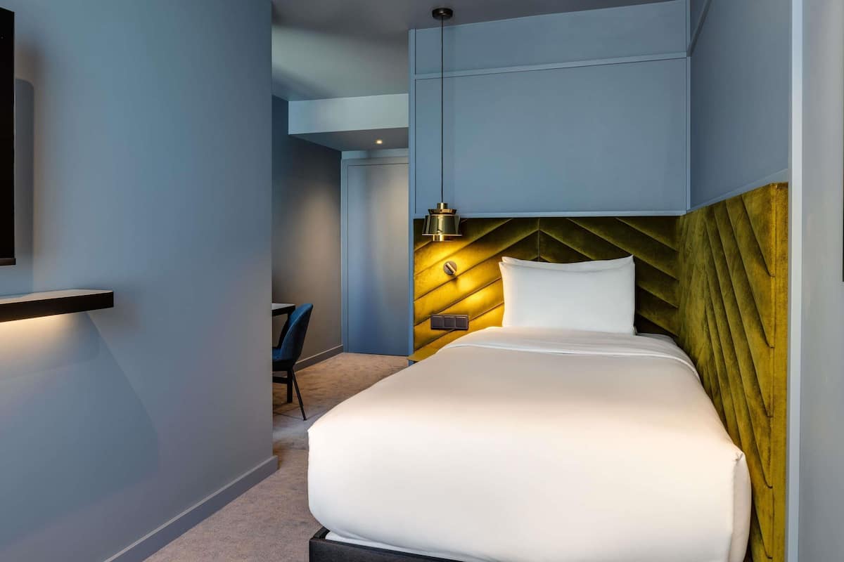 A modern hotel room with a bed, a desk, and a chair.