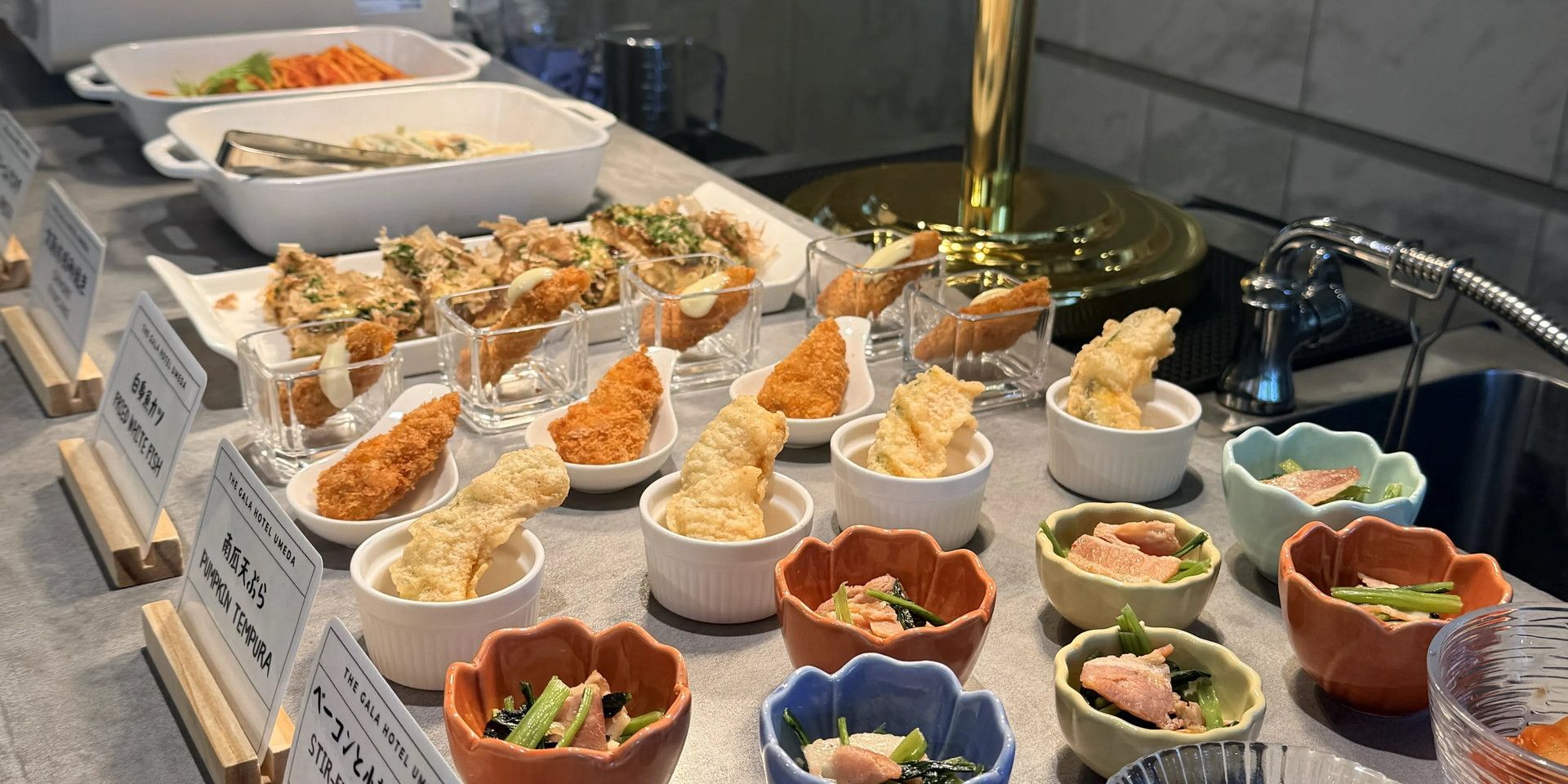 Een buffet met diverse gerechten, waaronder belegde snacks en kommen met eten, met labels die het soort eten aangeven.