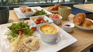 A table with various dishes including a salad, a baked dish, croissants, and small bowls of sauces. - The GALA Hotel Umeda (Osaka)