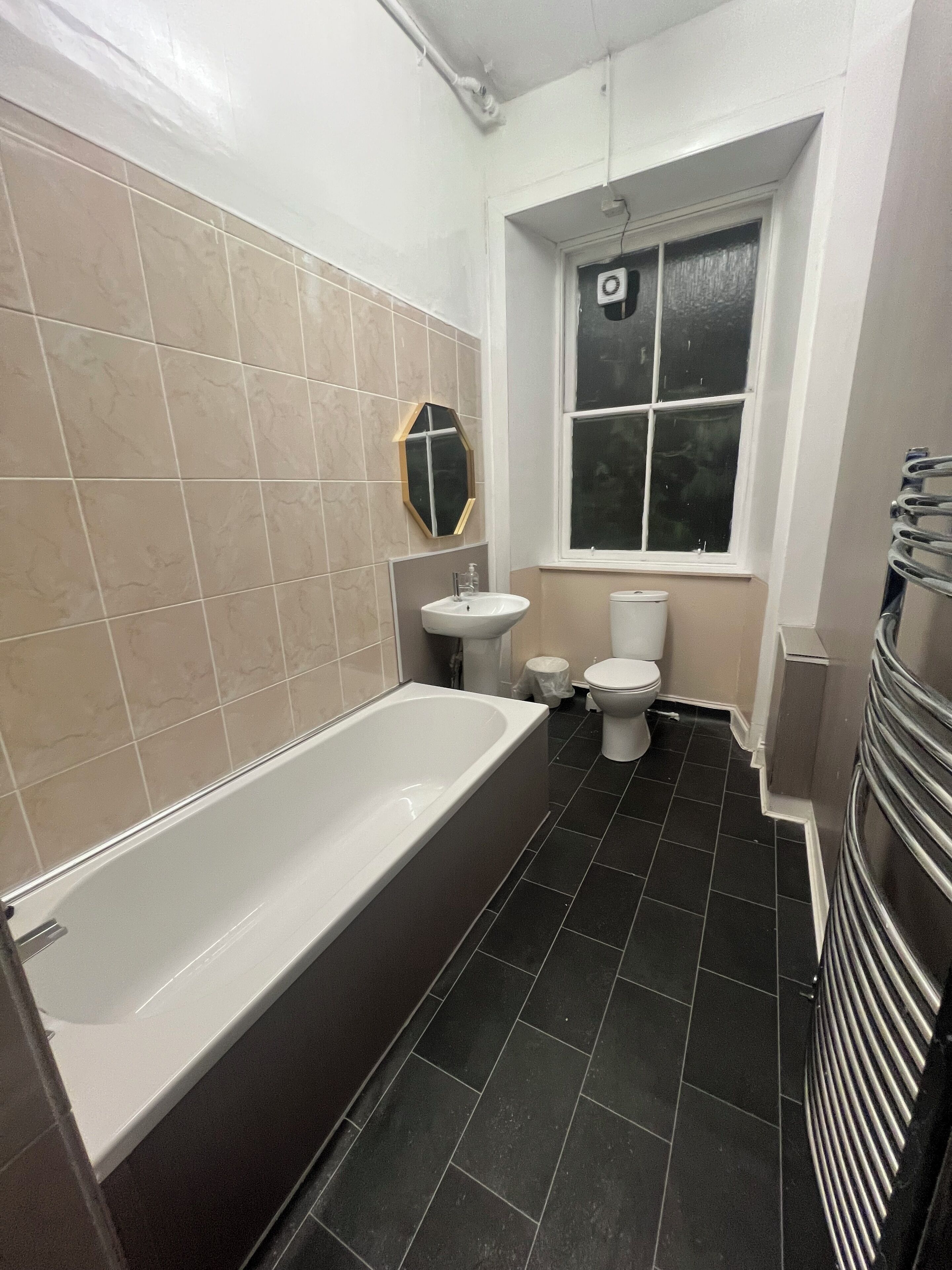A bathroom with a bathtub, sink, toilet, and a window.