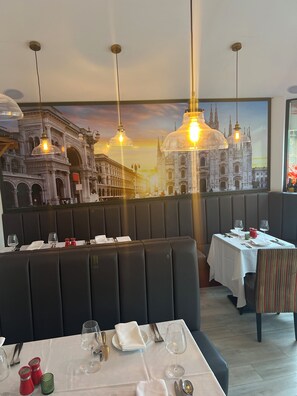 A restaurant with booth seating, tables set for dining, and a large cityscape mural on the wall. - Piccolo Hotel (Glasgow)