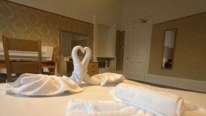 A hotel room with a neatly made bed, a heart-shaped towel arrangement, a wooden chair, and a mirror on the wall. - Piccolo Hotel (Glasgow)