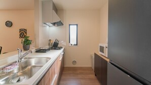A modern kitchen with stainless steel appliances, a built-in oven, and a microwave. - Travel Time Sumiyoshi Suzaku (Osaka)
