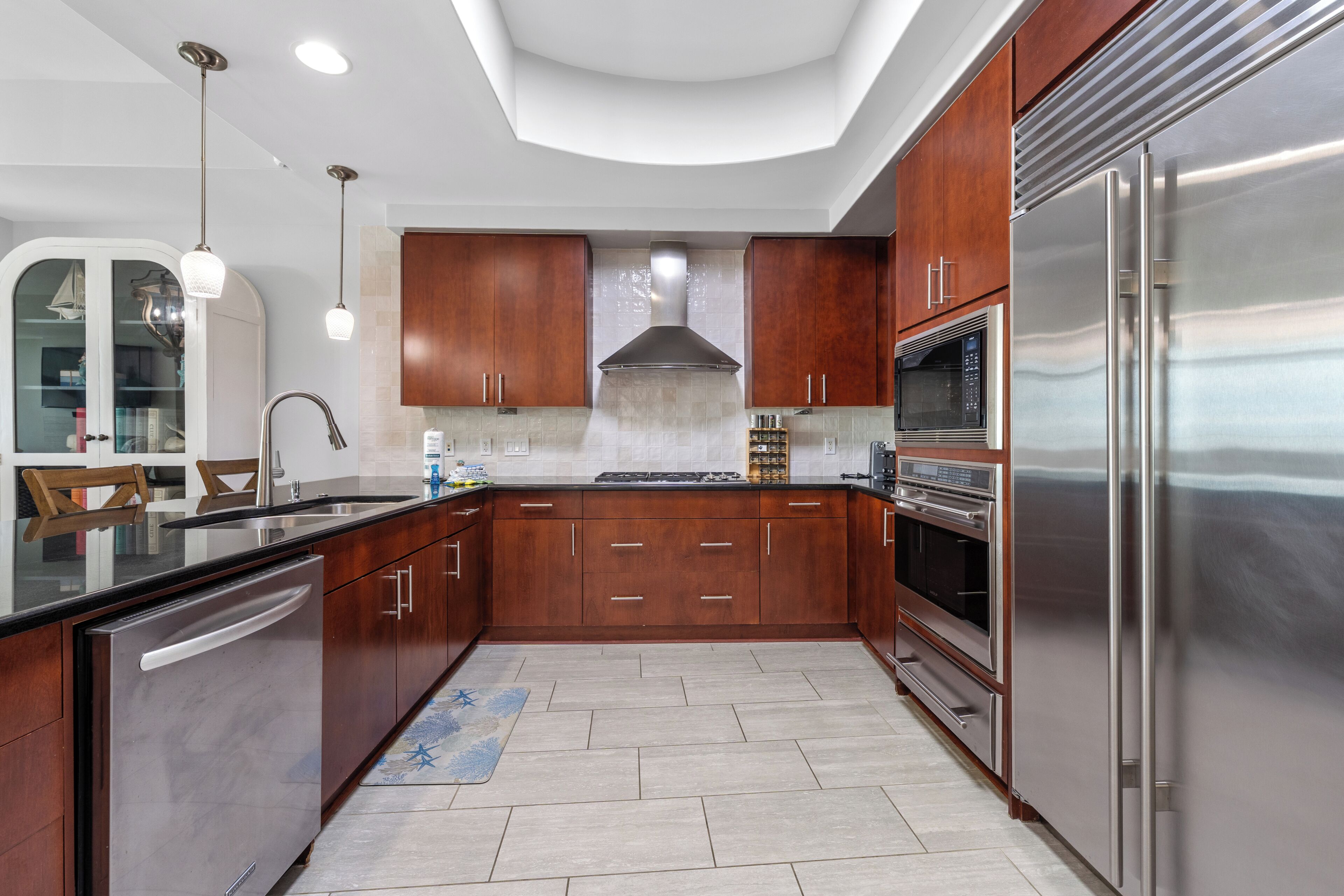 A modern kitchen with stainless steel appliances, wooden cabinets, and a built-in oven.