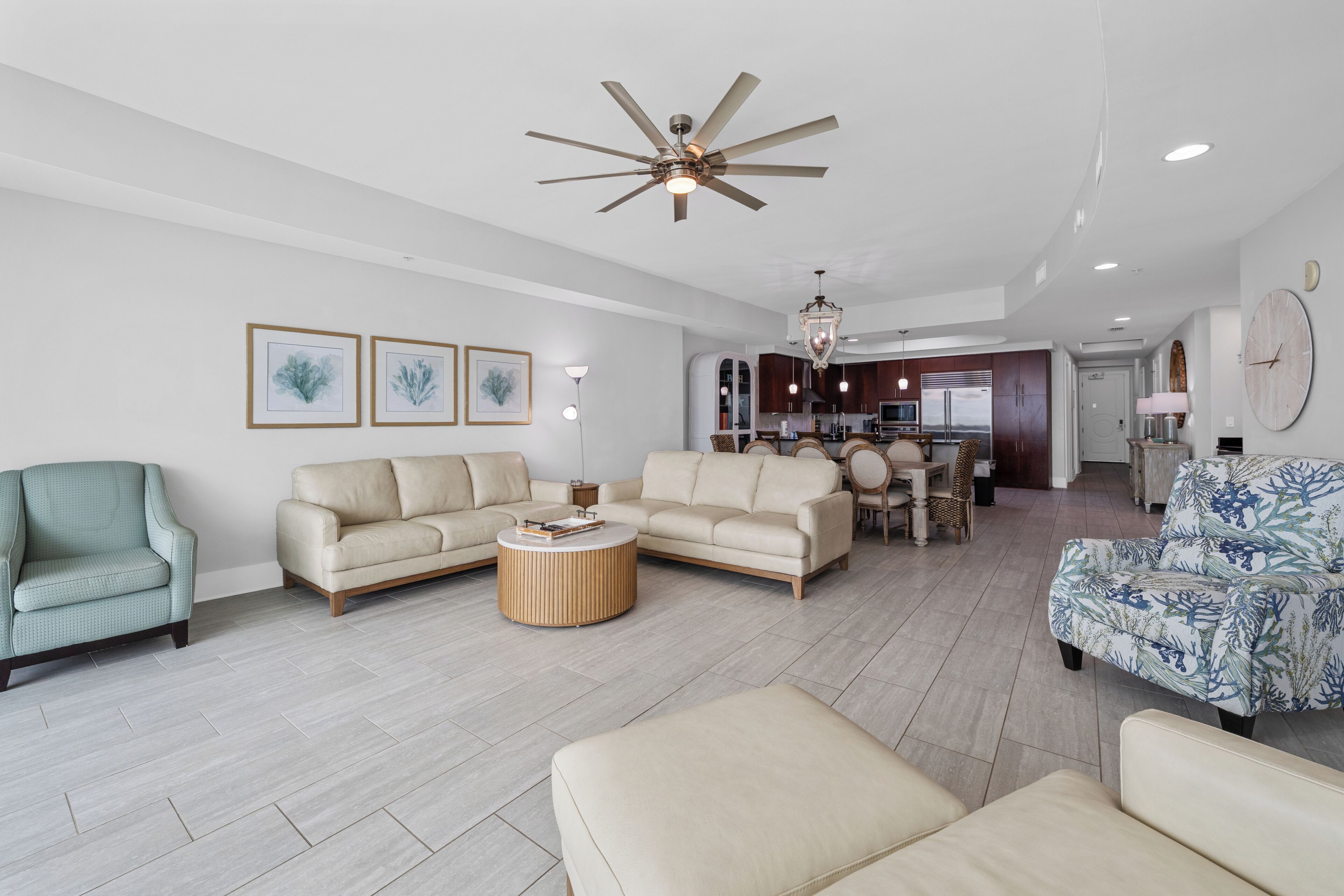 Ein geräumiges Wohnzimmer mit einer Couch, Sesseln, einem Couchtisch und einem Deckenventilator.