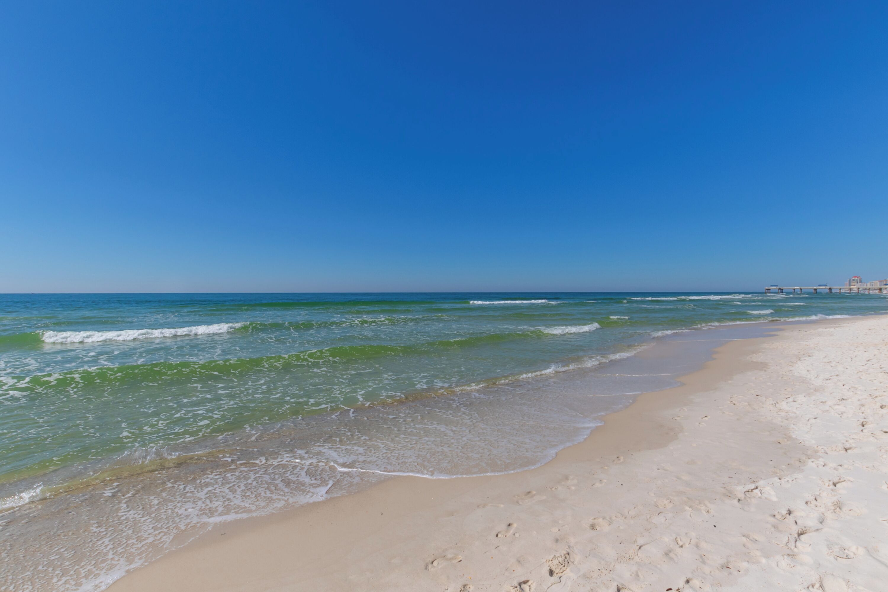 A beach with clear blue water and a sandy shore.