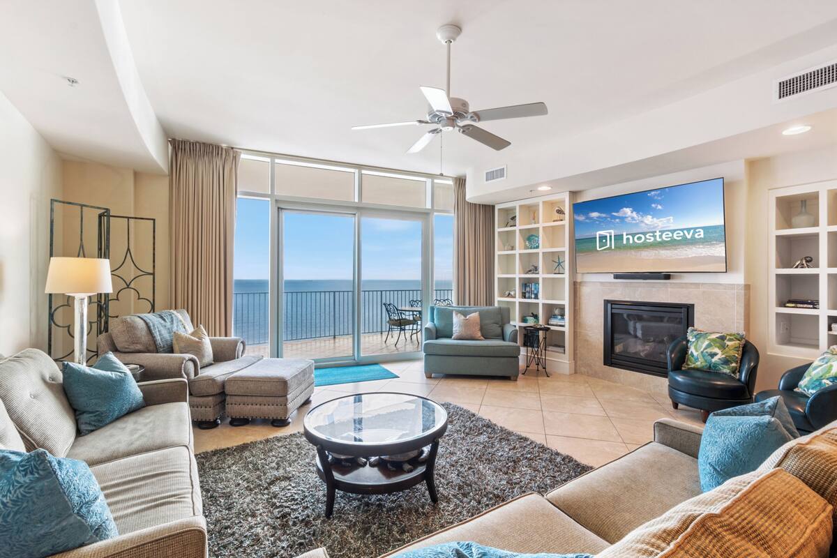 Un salon spacieux doté d’une grande télévision, de sièges confortables, d’une cheminée et d’un balcon offrant une vue sur la mer.