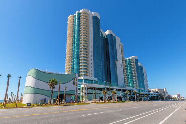 Ein modernes Hotel mit gewölbter Fassade, mehreren Stockwerken und blauem Himmel.