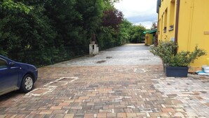 A paved driveway leading to a yellow building with a car parked on the left. - 3 Lofts for 9 People, Abete 3p, Noce 4p, Rovere 2p (Castel San Pietro Terme)