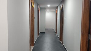 A long, narrow hallway with wooden doors on both sides, a tiled floor, and a ceiling light. - HOTEL BLACK GRAPES INN (Bhubaneshwar)