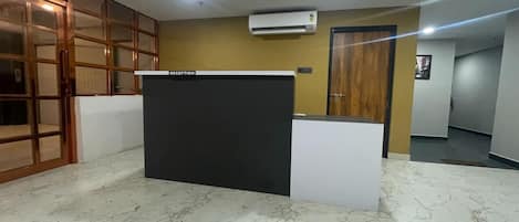 A reception area with a reception desk, a wooden door, and an air conditioning unit on the ceiling.