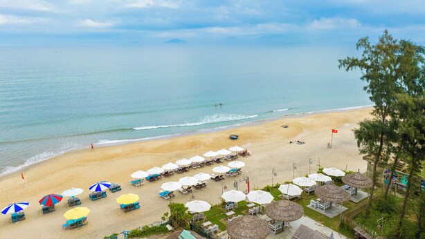 A beach with umbrellas, lounge chairs, and a flag. - Private Beachfront House 5BRs - An Bang Beach (Thành phố Hội An)
