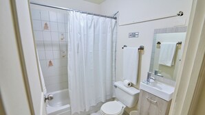 A bathroom with a bathtub, toilet, sink, and a mirror. - Modern Santo Domingo Condo in Heart of Gazcue (Santo Domingo)