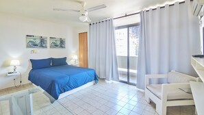 A bedroom with a bed, a chair, a ceiling fan, and a window with curtains. - Modern Santo Domingo Condo in Heart of Gazcue (Santo Domingo)
