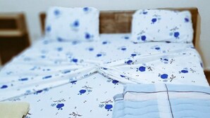 Una cama con una colcha estampada y una manta bien ordenada.
