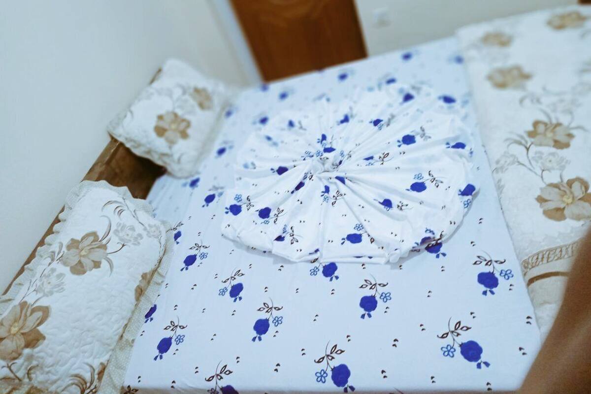 A neatly folded gift box with a bow, placed on a bed with floral-patterned bedding.