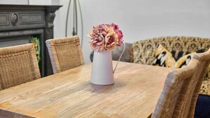 A dining table with a white vase of dried flowers, surrounded by wicker chairs. - Host Stay Railway Cottages (Liverpool)