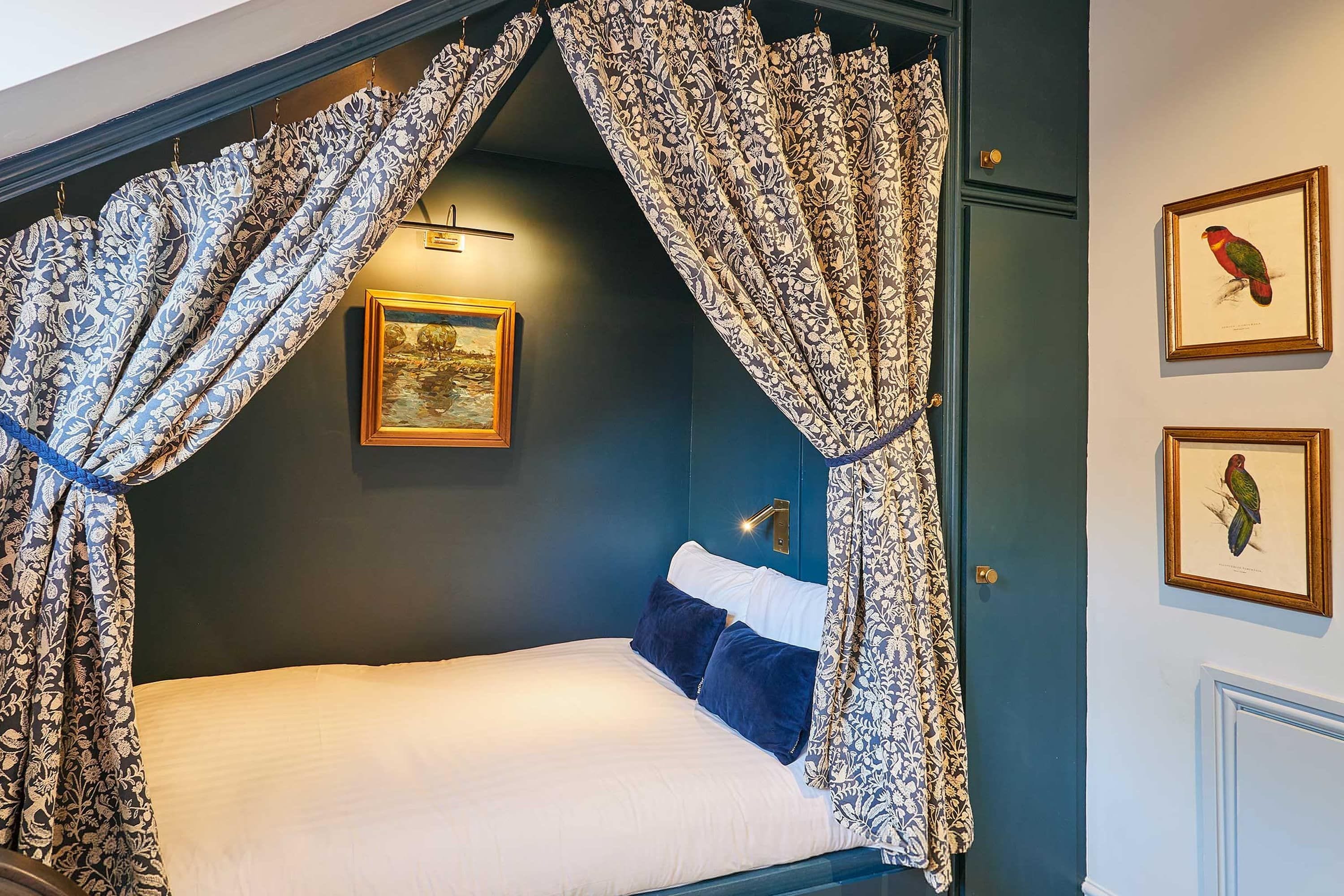A bedroom with a canopy bed, a framed picture on the wall, and a door with a bird illustration.