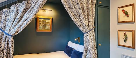 Un dormitorio con cama a dosel, un cuadro en la pared y una puerta con una ilustración de pájaro.