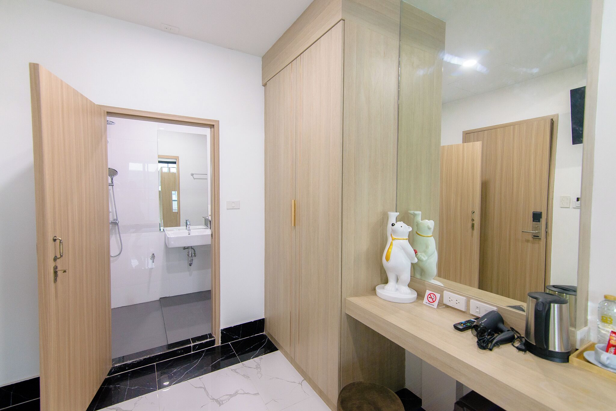 A modern bathroom with a wooden vanity, a large mirror, and a white bear statue.