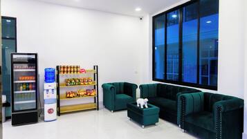 Um lobby moderno com máquina de vendas, prateleiras com lanches e um conjunto de sofá verde.
