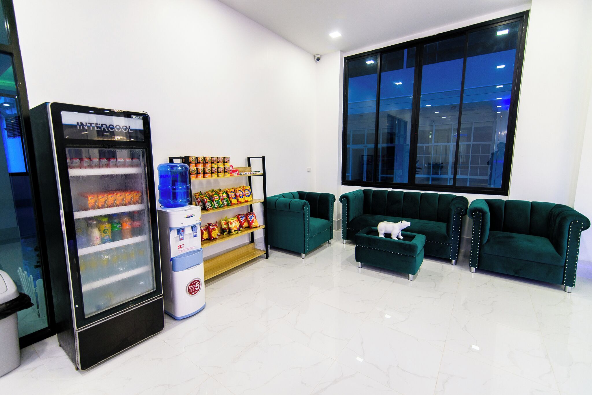 A modern lobby with a vending machine, seating area, and a large window.