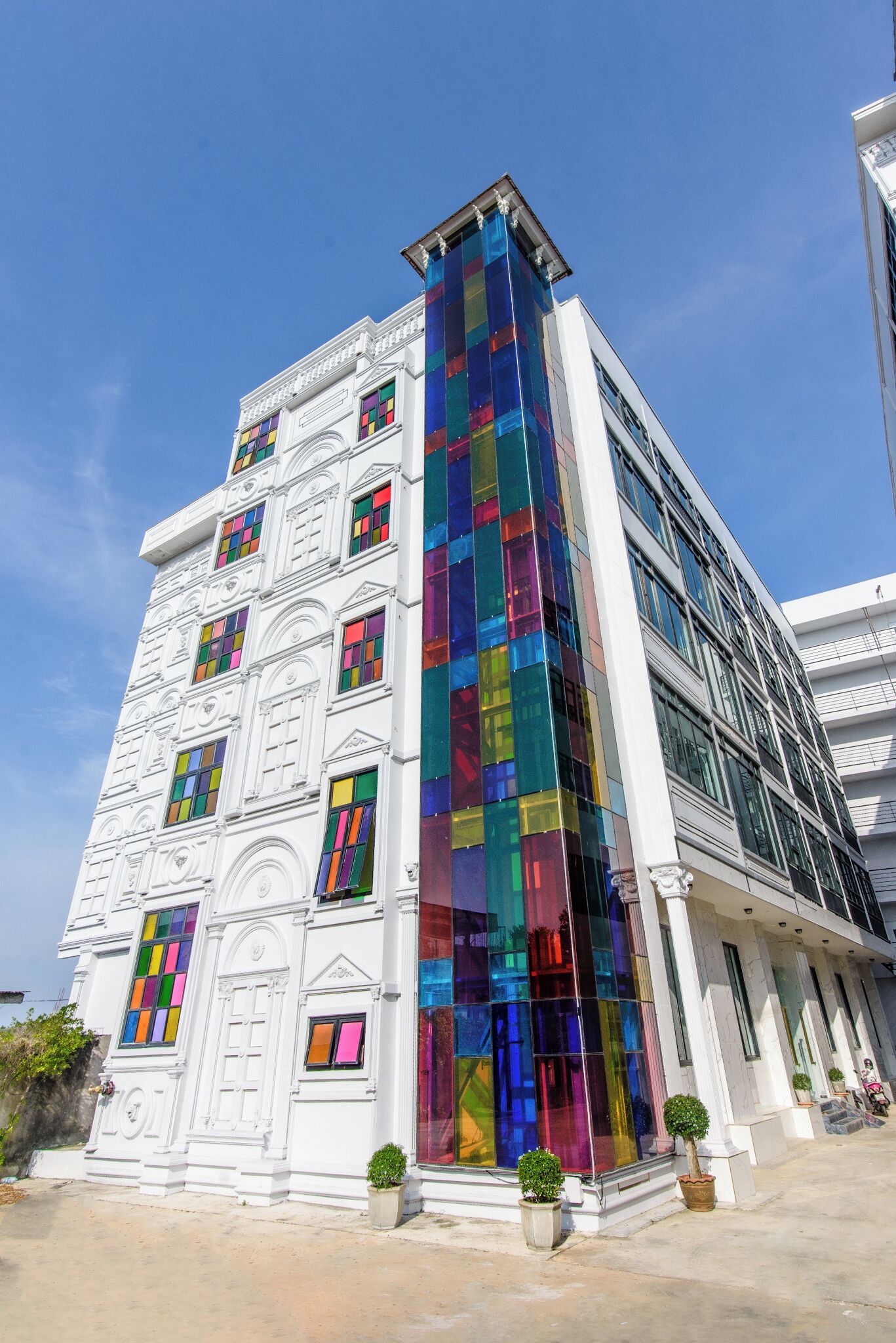Un edificio de varios pisos con fachada blanca y vidrieras de colores.