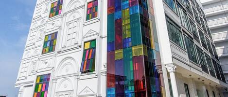 Un edificio de varios pisos con fachada blanca y vidrieras de colores.