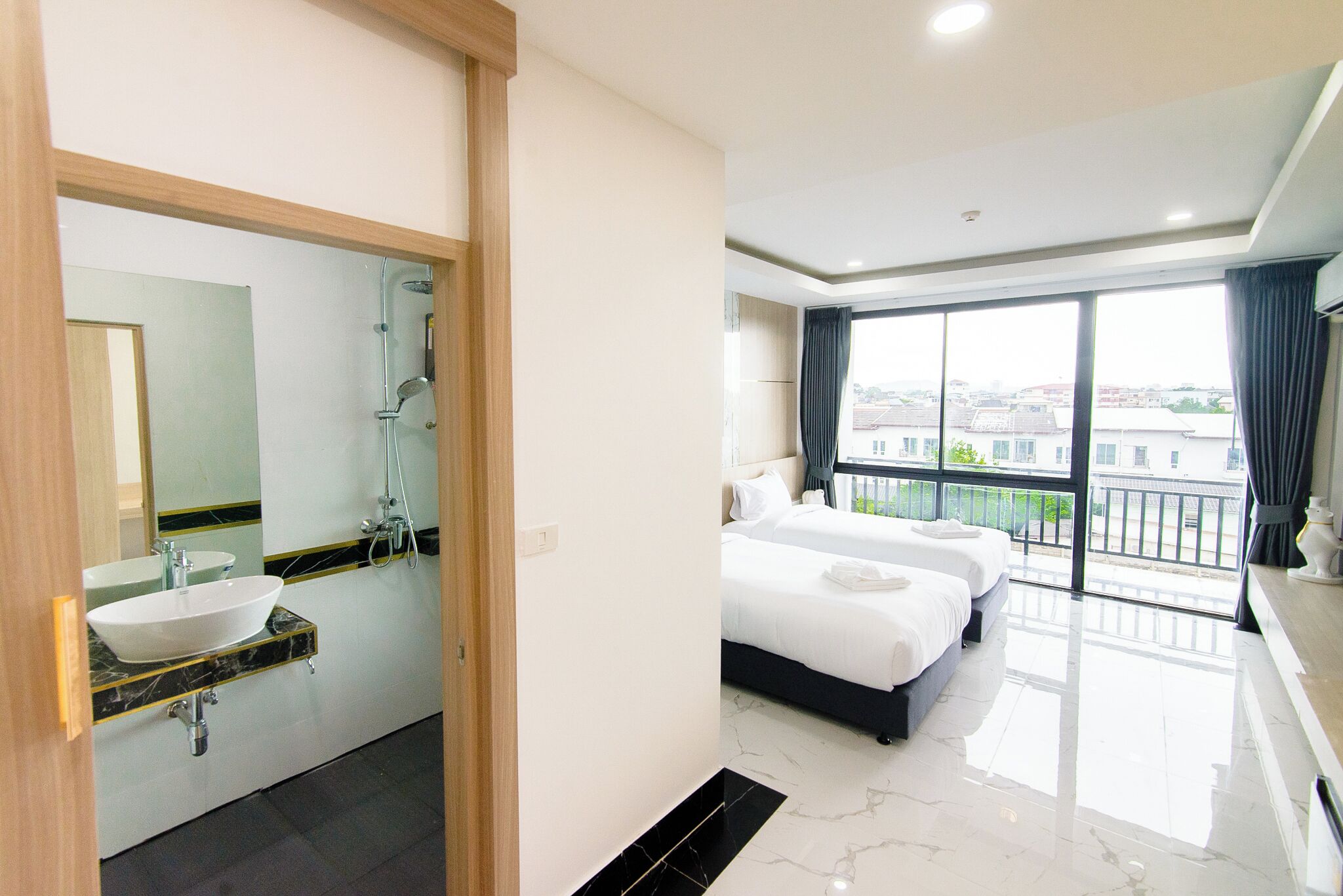 Habitación de hotel con baño, cama y una ventana grande con vistas.