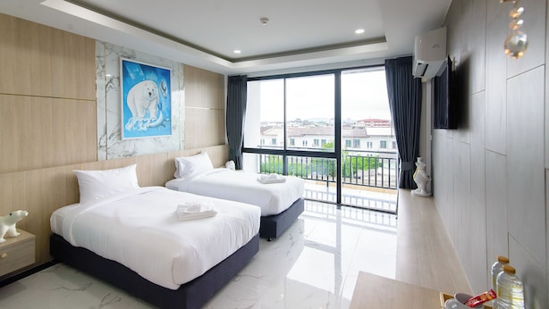A hotel room with two beds, a large window with a balcony, a painting of a polar bear, and a TV mounted on the wall. - Bear & Bird Hotel   (Surat Thani)