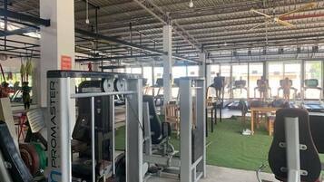 A gym with various exercise equipment, including a Promaster machine, and a green artificial turf area.