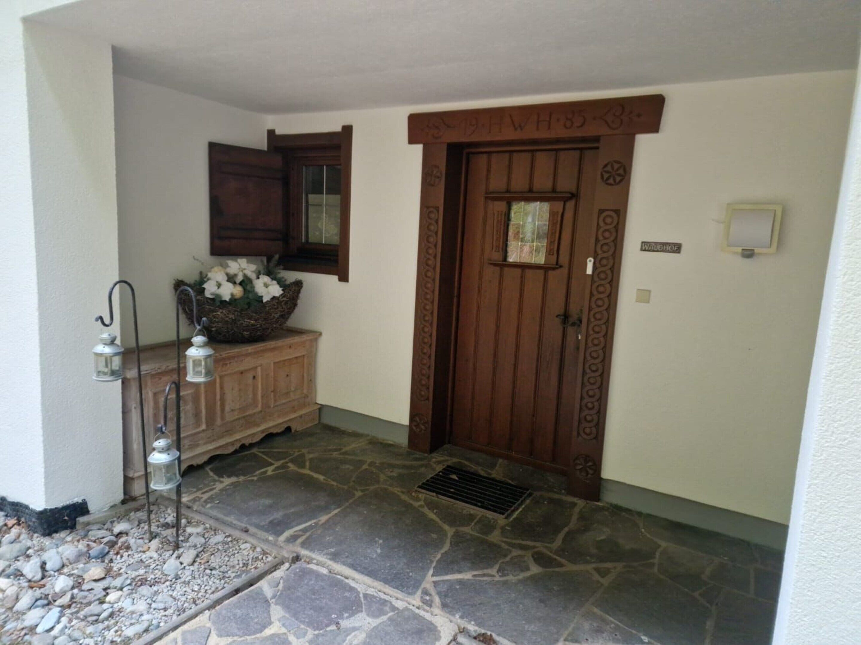 A stone-floored entrance with a wooden door and a small window.
