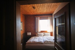 A wooden-paneled bedroom with a bed, curtains, and a window. - Amazing Cottage in Tyrol With Sauna (Volders)