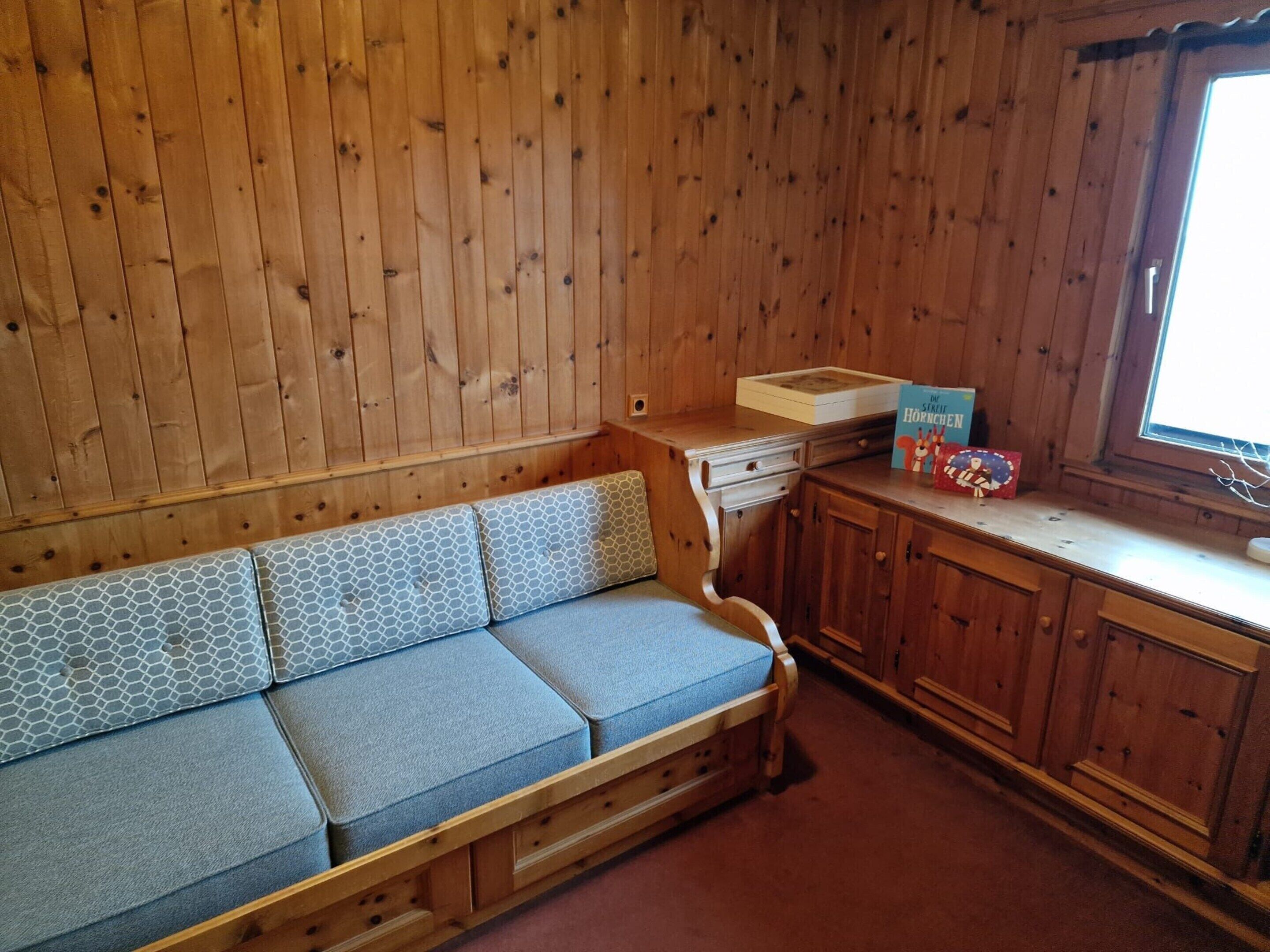 Ein Holzblock-Interieur mit einer Couch, einem kleinen Tisch und einem Fenster.