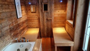Ein Badezimmer einer Holzhütte mit Badewanne, Sitzbank und Fliesenboden.