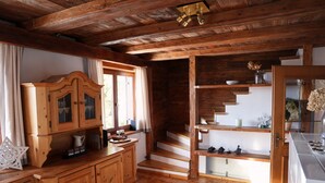 Ein Holzblock-Interieur mit Küchenbereich, Holzausstattung, einer Treppe und einem Esstisch.