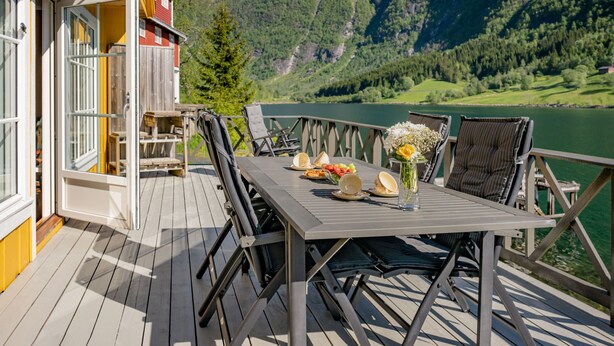 En terrasse med et spisebord, udsigt over en sø og bjerge.
