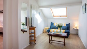 Un dormitorio tipo loft acogedor, con techo inclinado, tragaluz, cama, escritorio con computadora y sofá con cojín a rayas.