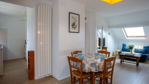 Un comedor con una mesa preparada para cuatro personas, sillas de madera y una lámpara colgante amarilla.