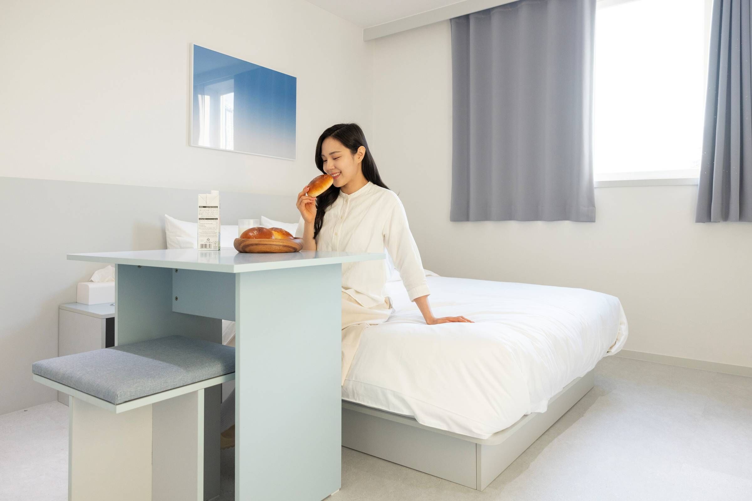 Une chambre à coucher moderne avec un lit, une table de chevet et une fenêtre avec des rideaux.